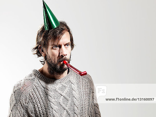 Mid adult man with party blower against white background