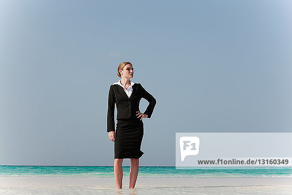 Geschäftsfrau am tropischen Strand stehend