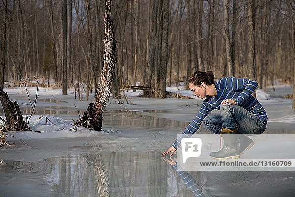 Frau testet schmelzendes Eis auf dem Teich