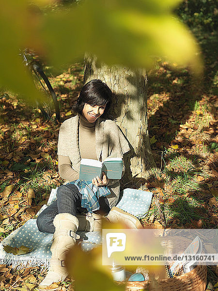 Woman reading under tree in Autumn