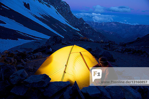 Woman unzips her tent at Camp One on Aconcagua in the Andes Mountains  Mendoza Province  Argentina