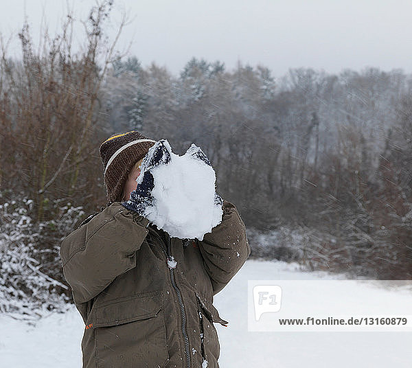Junge versteckt Gesicht hinter Schneeball