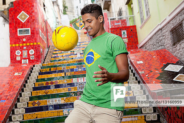 Junger Mann mit brasilianischem Oberteil  der vor der Treppe der Escadaria Selaron in Rio de Janiero  Brasilien  keepy uppys macht