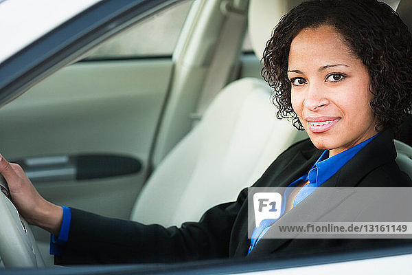 Woman in suit in car smiling