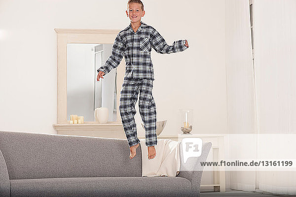 Junge im Schlafanzug springt auf Couch