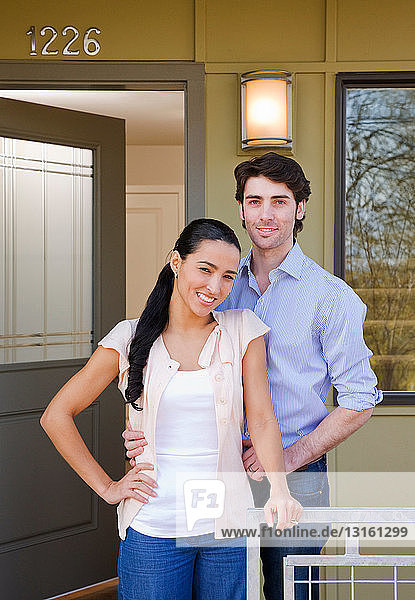 couple on front porch with sold sign