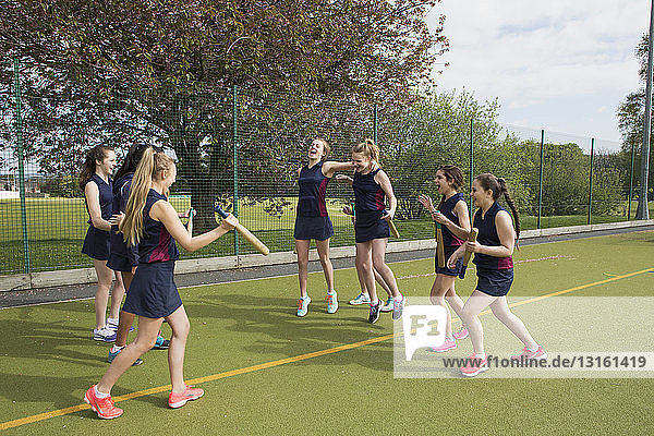 Gruppe von Mädchen auf einem Sportplatz mit Schlagballschlägern