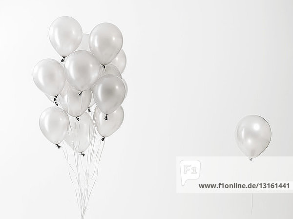 Silver balloons floating against white background