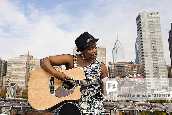 Ältere Frau spielt Gitarre vor der Skyline von Philadelphia  USA