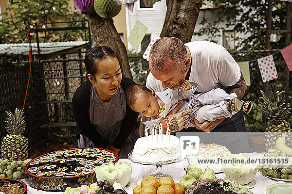 Parents and male toddler having birthday party in garden