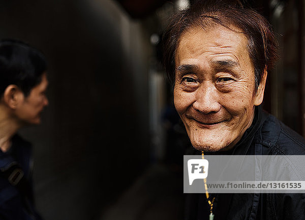 Porträt eines älteren Mannes mit Halskette  der lächelnd in die Kamera schaut