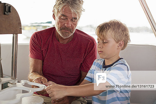 Großvater lehrt Enkel  auf Segelboot Knoten zu binden