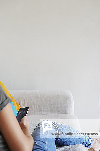 Frau benutzt Smartphone auf dem Sofa