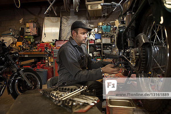 Mechaniker in seiner Garage beim Umbau von gasbetriebenen Motorrädern auf Bio-Diesel