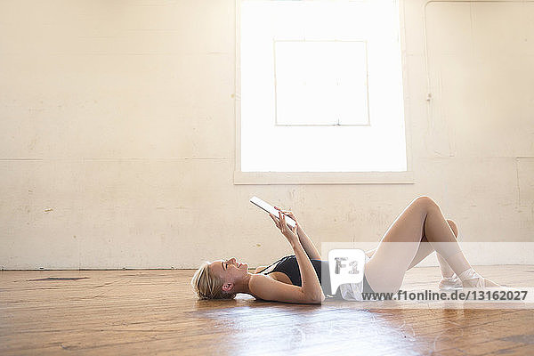 Balletttänzer liegt auf dem Boden und hält ein digitales Tablett