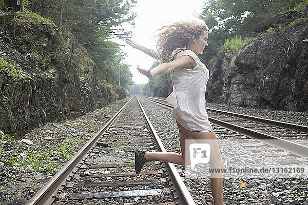 Teenager-Mädchen springt über Eisenbahnschienen