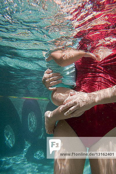 Mutter hält Tochter im Schwimmbad unter Wasser