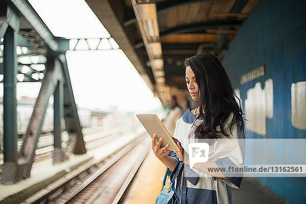 Mittelgroße erwachsene Frauen mit digitalem Tablet auf dem U-Bahn-Bahnsteig Brooklyn New York