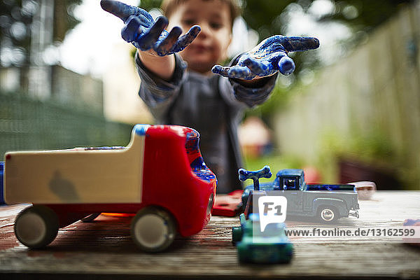 Junge spielt mit Spielzeuglastwagen und Aquarell