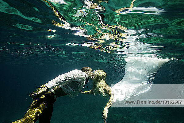 Paar in Hochzeitskleidung  küssend  unter Wasser