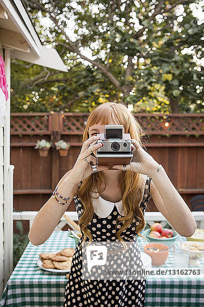 Junge Frau fotografiert mit Polaroidkamera