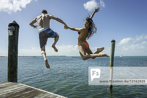 Rückansicht eines jungen Paares  das vom Seepier springt  Islamorada  Florida  USA