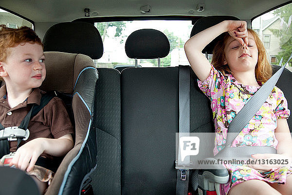 Mädchen macht Grimassen im Auto mit kleinem Bruder