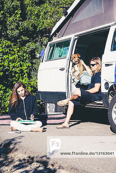 Couple with dog  relaxing by camper van