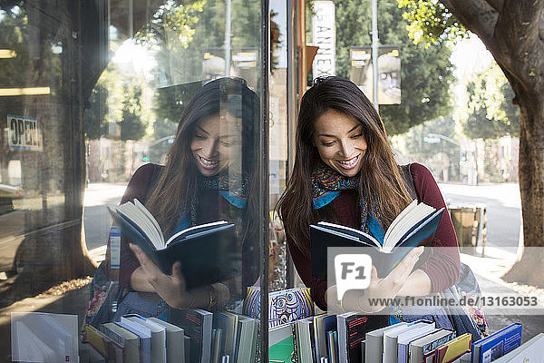 Junge Frau liest ein Buch im Schaufenster