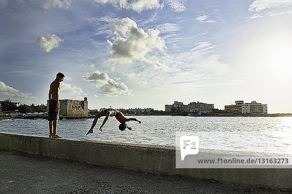 Zwei Jungen spielen und tauchen von der Hafenmauer  Havanna  Kuba