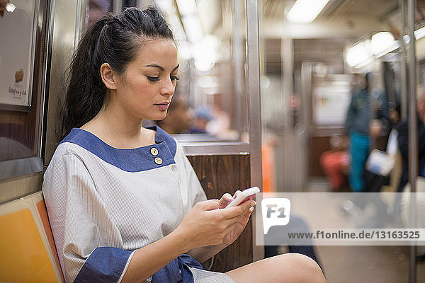 Mittelgroße erwachsene Frauen  die in der U-Bahn mobil telefonieren  New York
