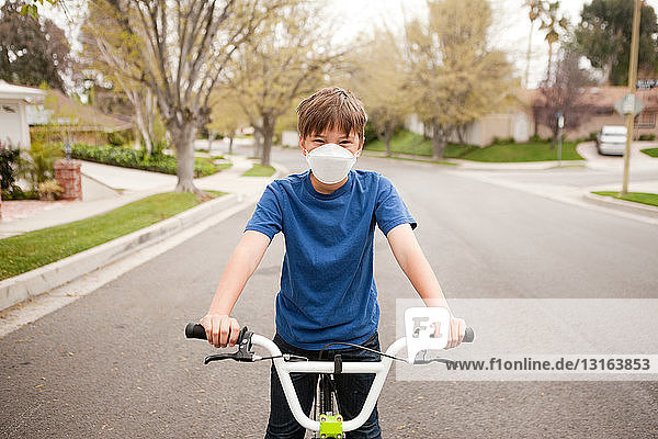 Junge auf Fahrrad mit Staubmaske