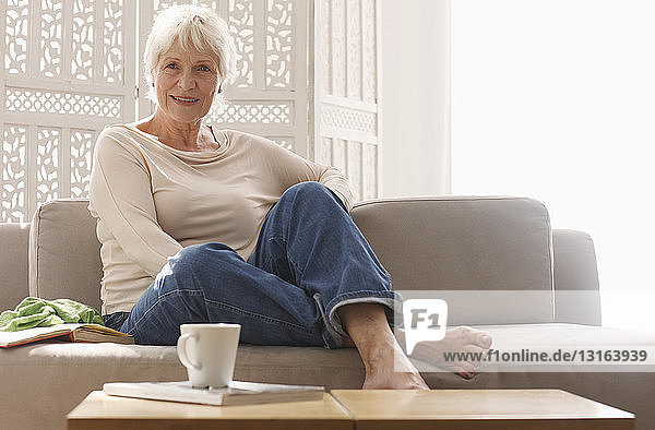 Ältere Frau entspannt sich zu Hause auf dem Sofa