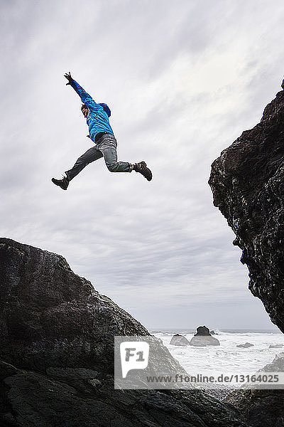 Man leaping over rocks Prairie Creek Redwoods State Park California US