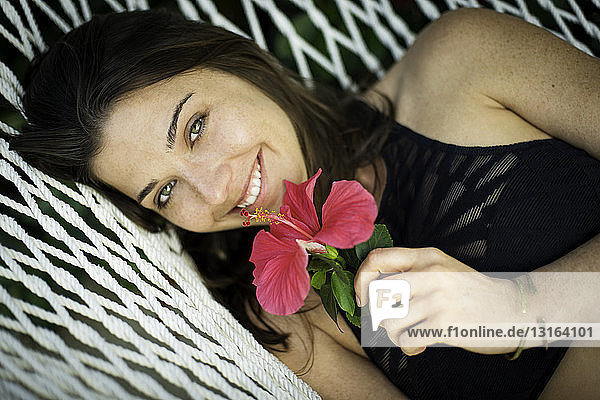Portrait of young woman on hammock with pink flower