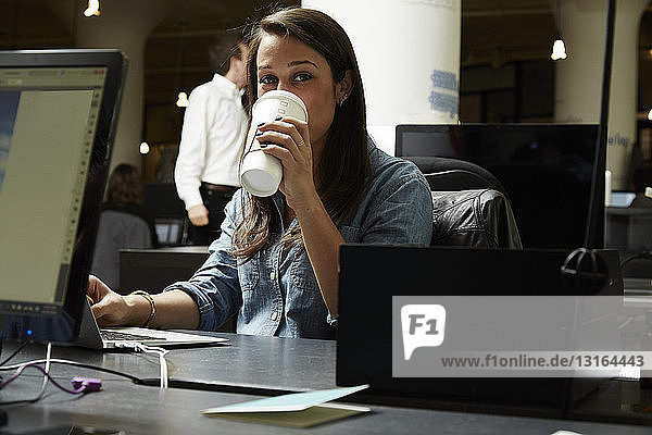 Junge Frau trinkt Kaffee im Büro