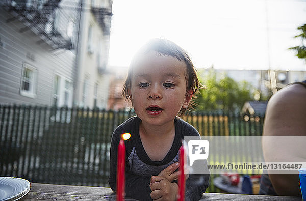 Boy looking at lit candle on dining table