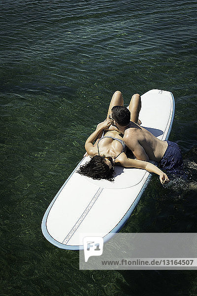 Draufsicht auf ein romantisches junges Paar auf einem Paddelbrett auf See