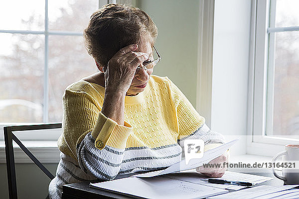 Ältere Frau liest am Schreibtisch