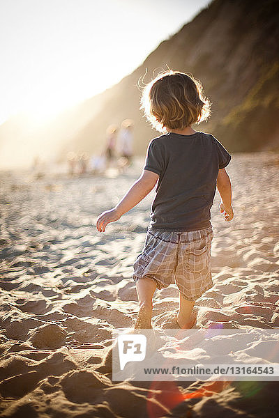 Kleiner Junge am Sandstrand bei Sonnenuntergang