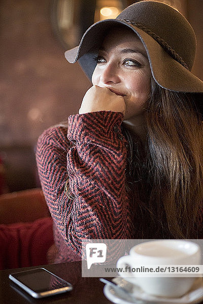 Porträt einer jungen Frau mit Hut  die sich auf den Ellbogen stützt