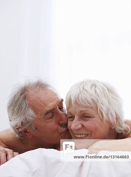 Älteres Paar küsst sich im Bett