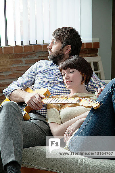 Junge Frau schläft neben einem Musiker auf dem Sofa