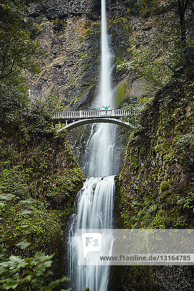 Male hiker crossing footbridge over Multnomah Falls Oregon USA