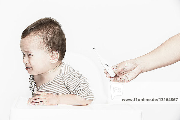 Baby weinender Junge  Digitalthermometer in der Hand haltend
