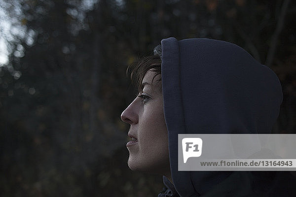 Close up portrait of mid adult woman gazing from forest at dusk