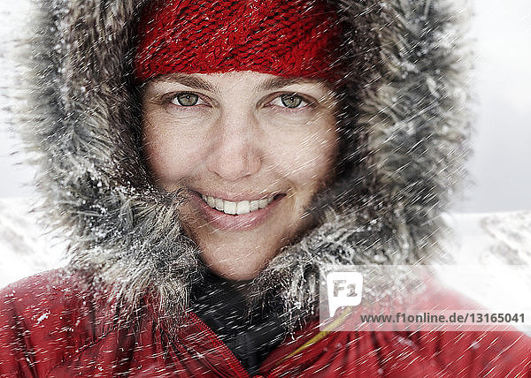 Nahaufnahme eines Porträts einer jungen Frau mit roter Kapuze im Schnee