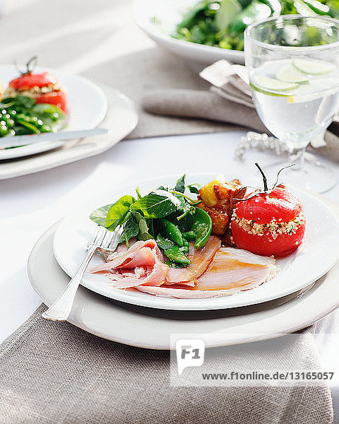 Teller von glasiertem Schinken mit gefüllten Tomaten und Spinat