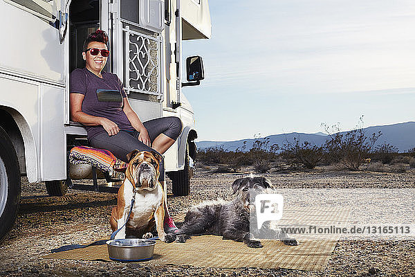 Porträt einer mittelgroßen erwachsenen Frau und zweier Hunde auf der Treppe eines Wohnmobils  Borrego Springs  Kalifornien  USA