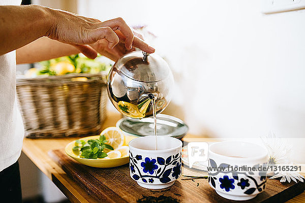 Frau bereitet Zitronen-Minze-Tee zu